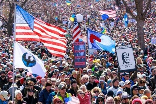 People hold flags and signs as a large crowd gather outside the Minnesota State Capitol in Saint Paul