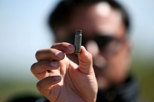 A man holds up a bullet casing found at the Mexican football field where at least 11 people were killed and scores wounded during an attack near the city of Salamanca