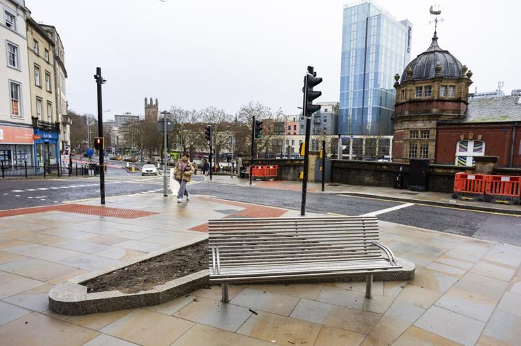 A newly installed bench directly faces a large stone wall