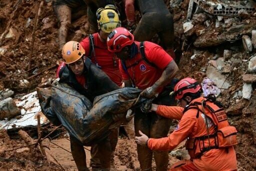 Firefighters carry a corpse found amid the debris after a landslide