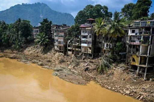 Uprooted trees lie along damaged buildings following a landslide in Gampola town, Kandy district, on December 4, 2025