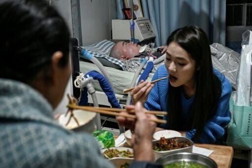 Even with the help of her daughter, Wu (front, back turned) only sleeps three to five hours a night, but says the family is "quite happy" despite their difficulties