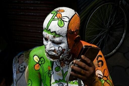 A supporter with the All India Trinamool Congress (TMC) party in West Bengal listens to his phone during vote counting