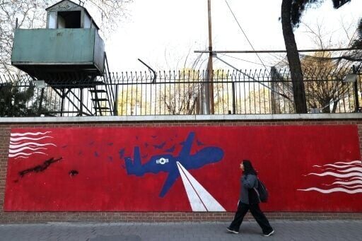 A woman walks past a mural depicting a US drone painted on the outer walls of the former US embassy in Tehran