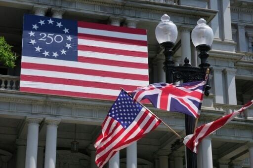 US and UK flags are flying near a flag celebrating the United States' 250th anniversary of independence for the visit