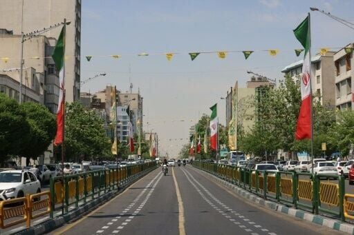 Vehicles drive along a street adorned with Iranian flags at Revolution Square in Tehran on Tuesday