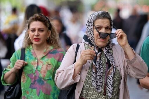 Iranian women walk along a busy street in Tehran