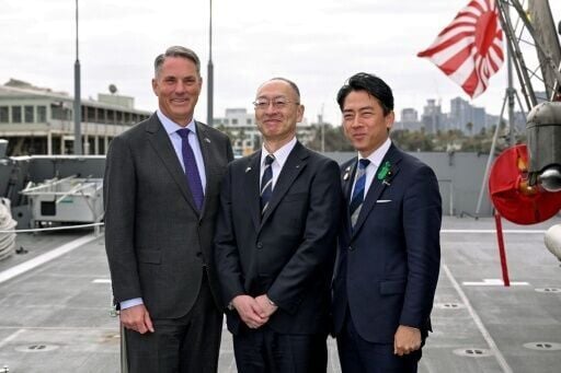 (FILES) Australia's Deputy Prime Minister and Minister for Defence Richard Marles (L) and Japan's Minister of Defense Koizumi Shinjiro (R) pose for a photo with Eisaku Ito, President and CEO of Mitsubishi Heavy Industries, before the signing of the cont...