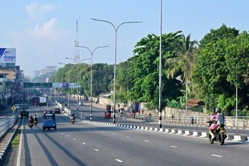 Commuters ride along a deserted street in Colombo on March 25, 2026. Sri Lanka has ordered street lights, neon signs and billboard lighting to be switched off as part of measures to cut energy consumption by 25 percent.