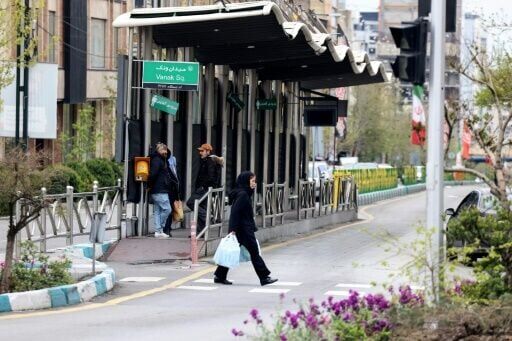 An Iranian woman walks past a bus stop in Tehran on March 31, 2026