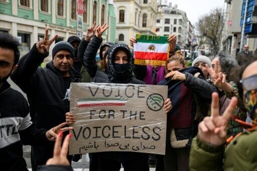 Protesters hold a placard reading "Voice for the voiceless" and the flag of Iran from before the 1979 revolution during a demonstration outside the Iranian Consulate in Istanbul