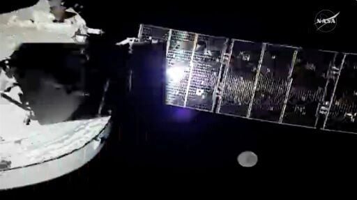 A NASA livestream shows the Orion spacecraft with one of its four solar array panels, with the Moon in the distance