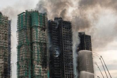 People searching for missing loved ones lined up at a Hong Kong community hall in the shadow of smouldering apartment blocks to leaf through photos of the deceased