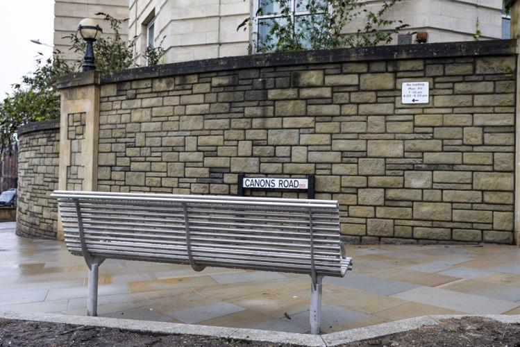 A newly installed bench directly faces a large stone wall