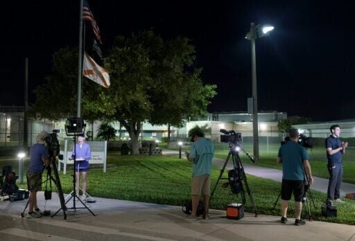 Media members report from in front of the Martin County Jail, where golfer Tiger Woods was held after being arrested on a charge of driving under the influence a car crash