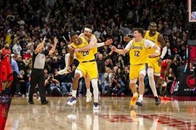 Rui Hachimura of the Los Angeles Lakers celebrates with teammates Austin Reaves, Jake LaRavia and Deandre Ayton after making the game-winning three-pointer in an NBA victory over the Toronto Raptors