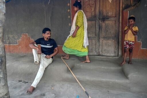 Raju Modiyam, who lost a leg in a landmine explosion, rests as his wife Jayamma and child look on at their residence in Lankapalli village