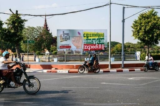 Motorists drive past a billboard that translates as "From the election to a better future" in Mandalay on January 25