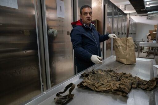 Anthropologist Ditor Haliti shows garments found in the grave of an unidentified individual