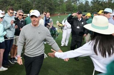 Defending champion Rory McIlroy of Northern Ireland high-fives spectators as he walks to the 10th tee at Augusta National during a practice round ahead of the 90th Masters