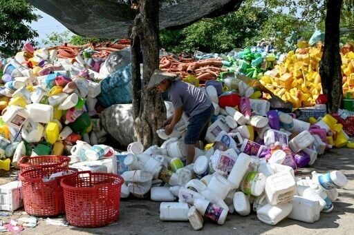 A worker handling plastic bottles before they can be melted into tiny pellets for reuse