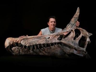 US paleontologist Paul Sereno poses next to the skull cast