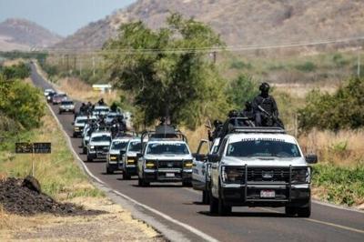 Security forces patrol a highway after a wave of violence in the Mexican town of Aguililla, the birthplace of drug kingpin Nemesio Oseguera, who died after a shootout