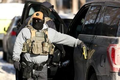 Federal agents stand by a vehicle after they detained a protester in Minneapolis, Minnesota