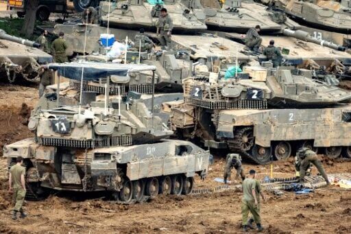 Israeli soldiers work on the belts for their tanks at a staging area in the Upper Galilee in northern Israel near the border with Lebanon on March 13, 2026