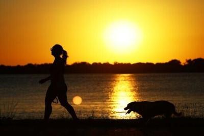A woman walks her dog at sunset in Porto Alegre, Brazil