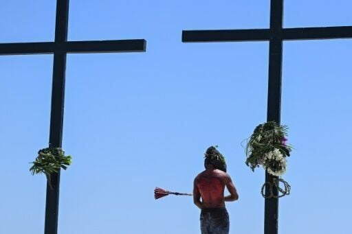 A man punctures the skin of Filipino penitents before they begin flagellating themselves on Good Friday