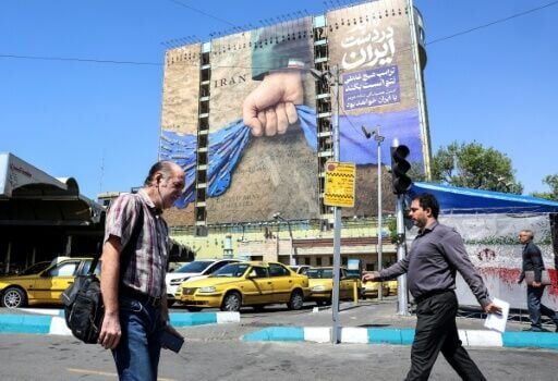 Iranians walk past a billboard referring to the Strait of Hormuz in Tehran's Vanak Square on April 15, 2026