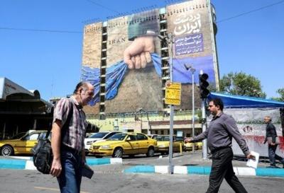 Iranians walk past a billboard referring to the Strait of Hormuz in Tehran's Vanak Square on April 15, 2026
