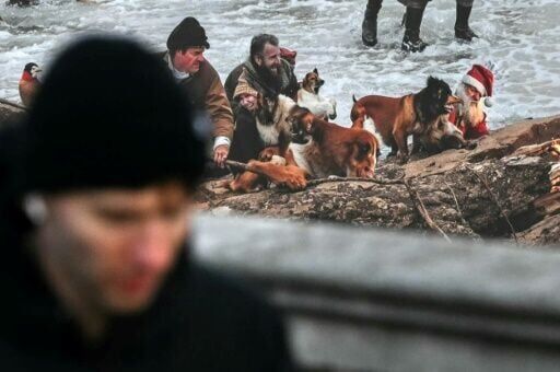 A Father Christmas figure is pictured looking pained in the water at the foot of a rock, his eyes shut and his beard half orange