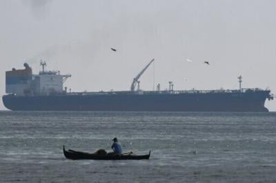A fisherman paddles before the Sierra Leone-flagged Sara Sky, which is carrying crude oil from Russia, anchored at Limay port, Bataan province on March 26, 2026