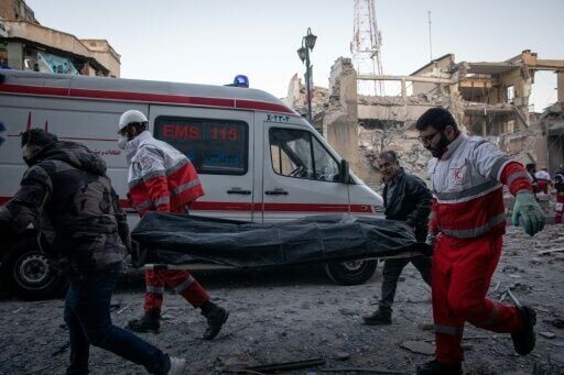 Rescue workers carry the body of a victim after a strike on a building in Tehran's Enghelab Square