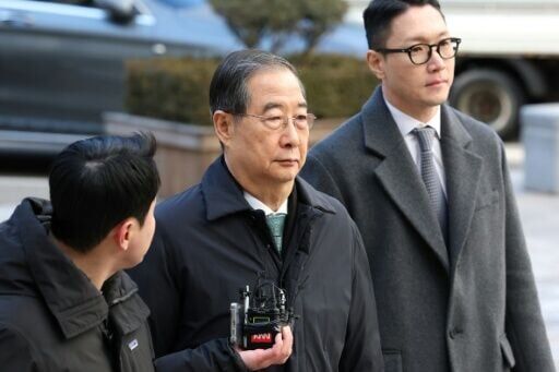Former South Korean prime minister Han Duck-soo (C) arrives at the Seoul Central District Court for his first sentencing trial in the insurrection case in Seoul on January 21, 2026
