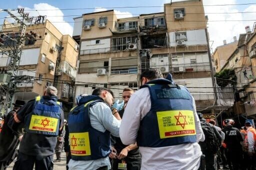 Israeli security forces and first responders gather outside a building hit by an Iranian projectile strike at a residential neighbourhood in Bnei-Brak, on the eastern outskirts of Tel Aviv