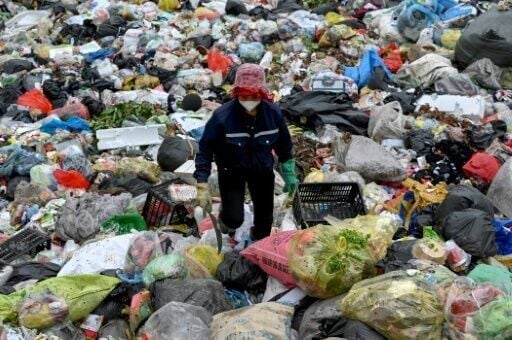 A woman picks up plastic waste at a landfill on the outskirts of Hanoi
