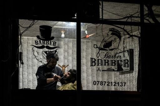 An Afghan barber trims a customer's beard at a salon in Kabul