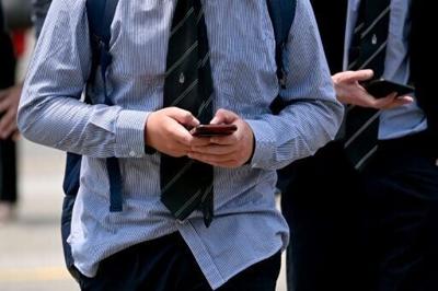 Young people looking at their phones in Australia, which has enacted a world-leading ban restricting teens' access to social media.