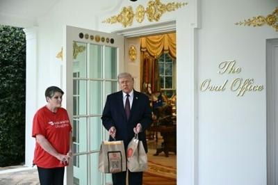US President Donald Trump holds McDonald's bags outside the Oval Office at the White House, in Washington, DC, April 13, 2026.
