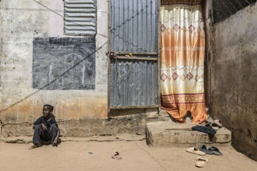 Coumba, who lost her father to a pirogue accident in 2022, sits outside her home in Mbour, Senegal