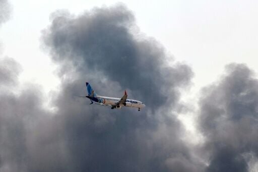 A plane comes into land as smoke rises near Dubai International Airport