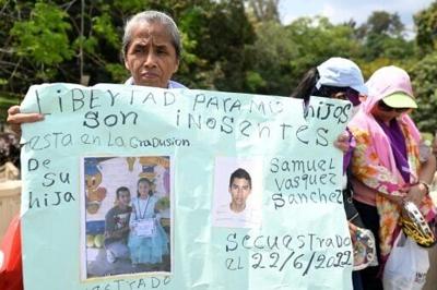 A woman holds a sign demanding the release of relatives detained under President Nayib Bukele's massive anti-gang crackdown