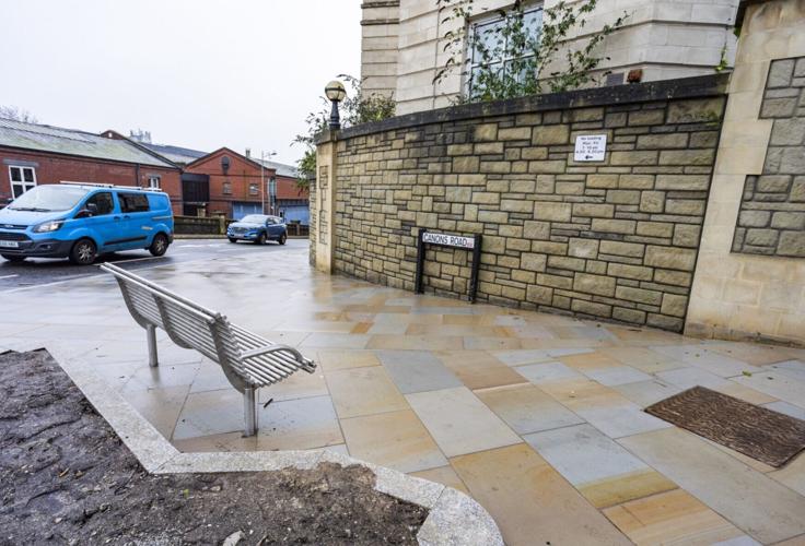 A newly installed bench directly faces a large stone wall
