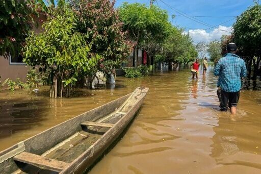 People walk on a flooded street in Lorica, Colombia