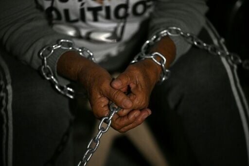 A relative of a political prisoner remains chained outside the prison in Caracas