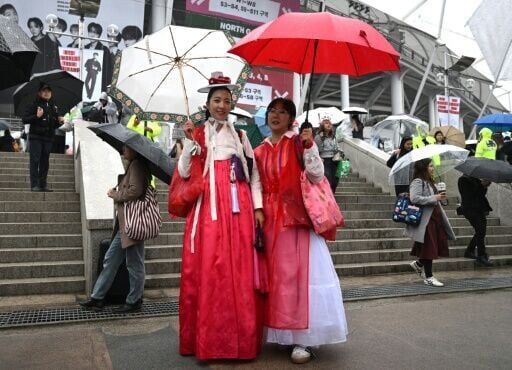 BTS fans wearing traditional Korean hanbok pose for a photo as they arrive at a stadium where K-pop boy band BTS will perform in Goyang on April 9, 2026.