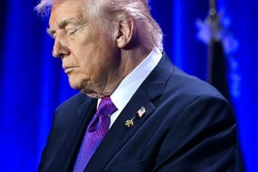 US President Donald Trump bows his head in prayer during the National Prayer Breakfast